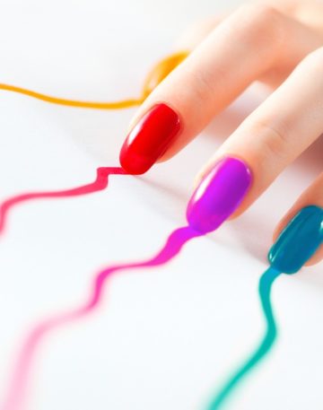 Young woman hand with multicoloured nails. On white.